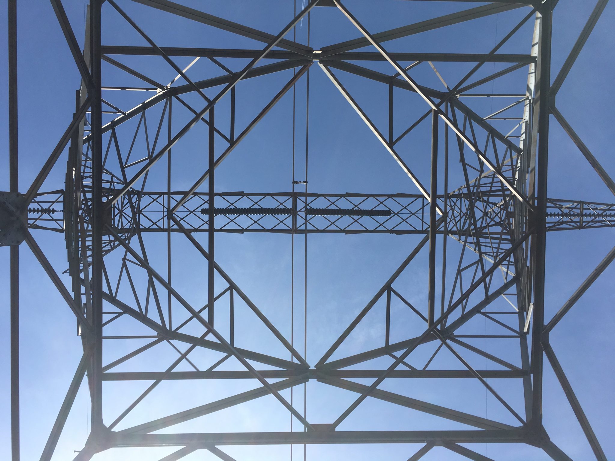 Looking up at a power line tower